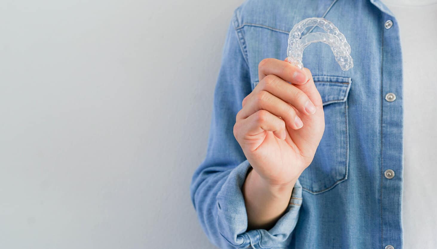 Novedades De Invisalign® 1 rsz man hand holding dental aligner retainer invisible on background